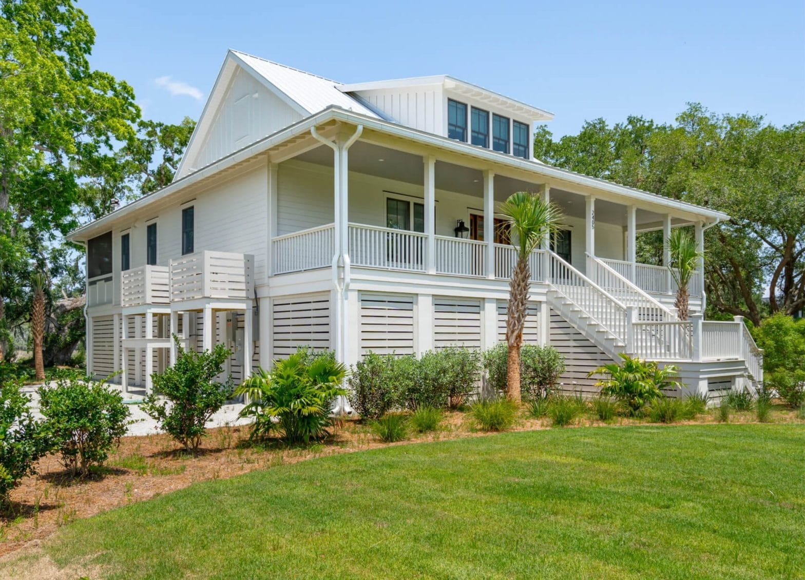 White custom home with a spacious covered porch and landscaped yard